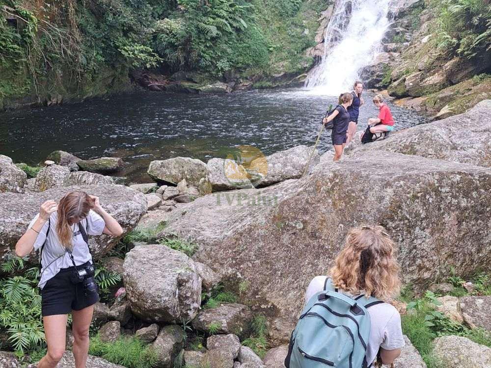 Tourists admiring a waterfall during their 2-day Tay Con Linh trekking hike