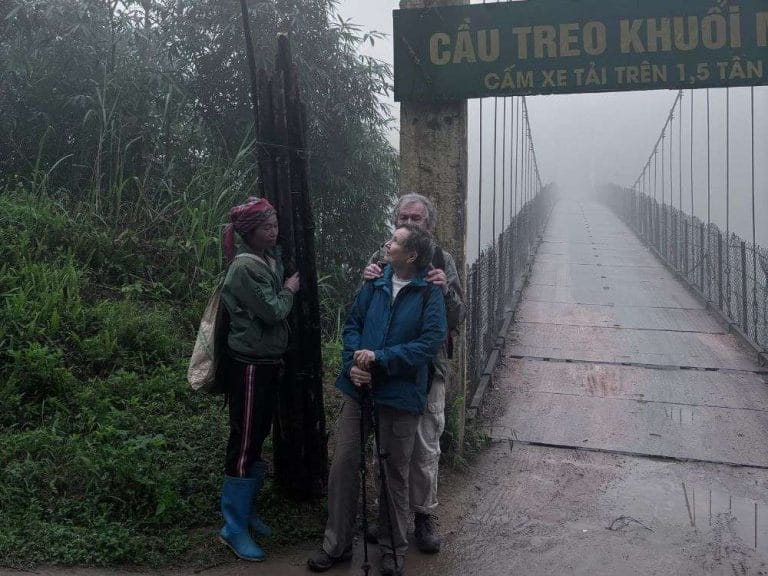 Tourists pose with local sign near Dao Ao Dai Villages suspension bridge