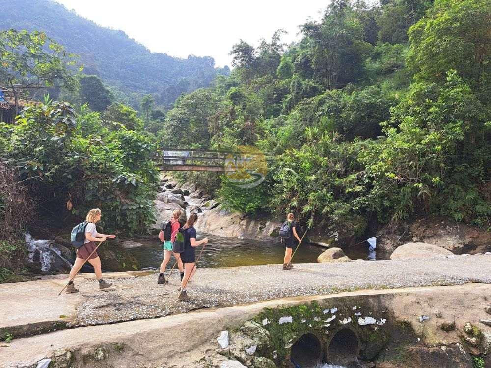 Trekkers crossing a stream on the route of a 2-day Tay Con Linh trekking trip