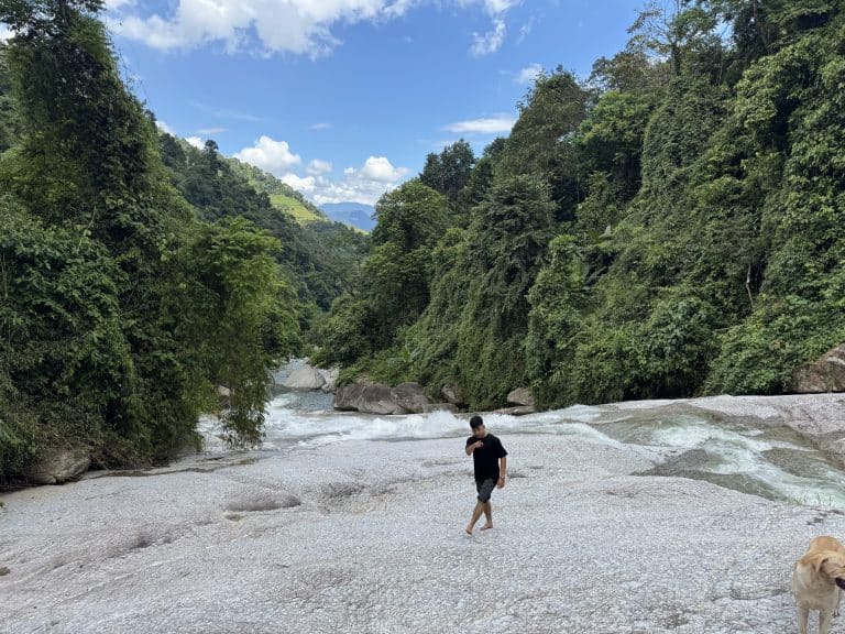 A walker on the granite slab beside the clear pool below Lung Vai Waterfall