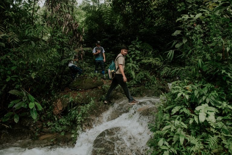 A guide crossing a stream on the forest trail down to Lung Vai Waterfall