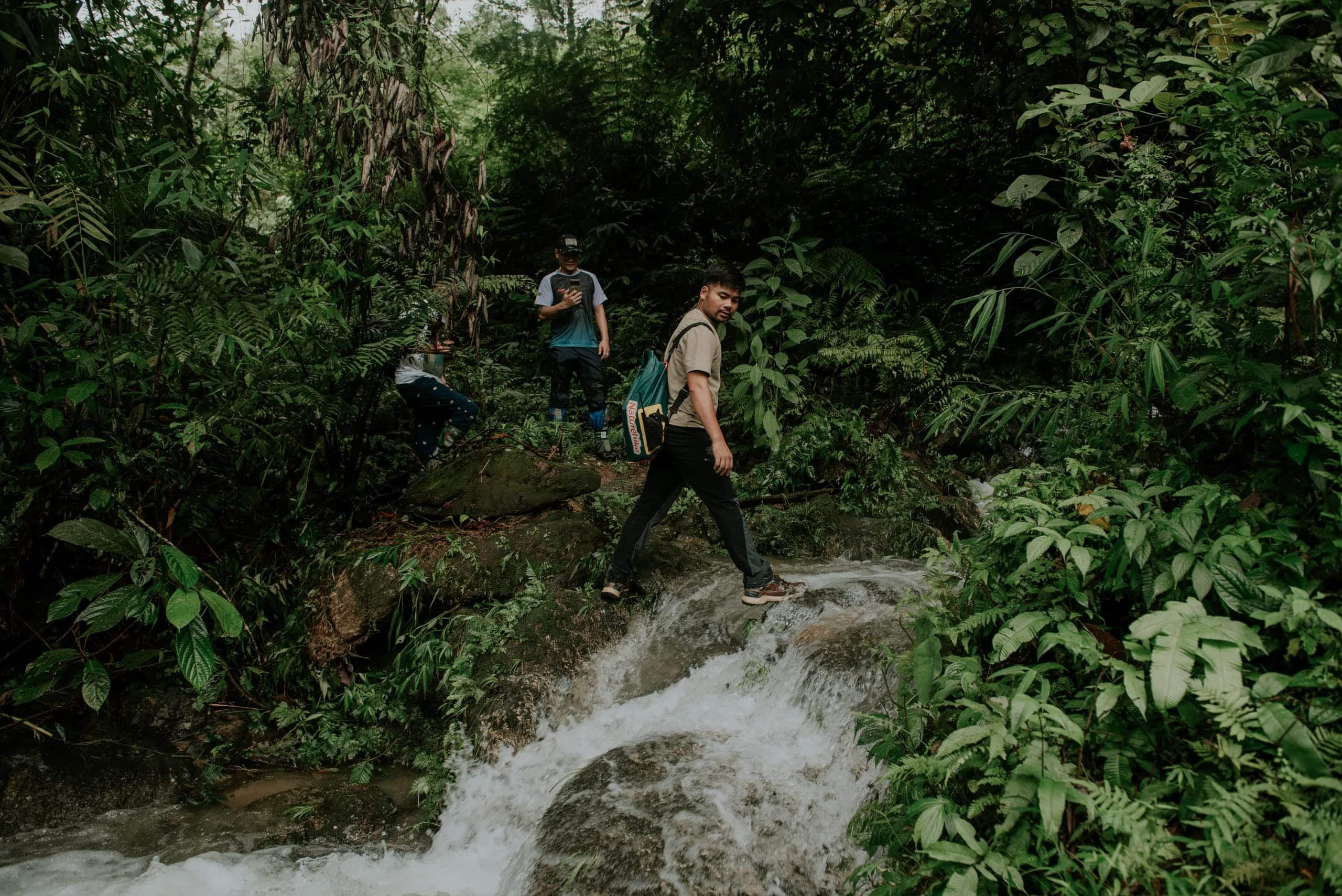 A guide crossing a stream on the forest trail down to Lung Vai Waterfall