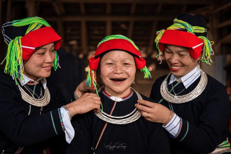 Dao Ao Dai women helping an elder with her silver necklaces