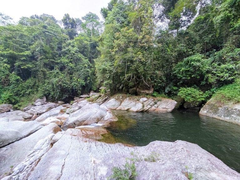 Emerald pool and pale granite boulders on the Lung Vai stream, with forest along both banks