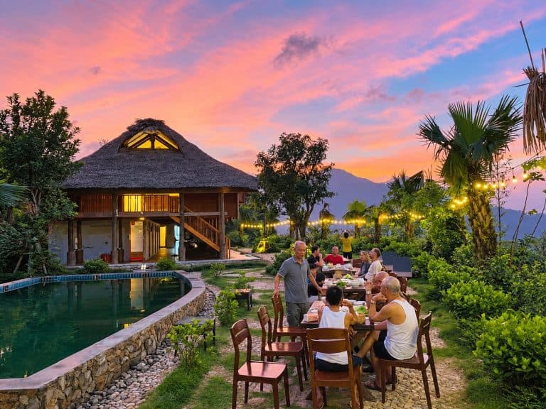 Guests having dinner outdoors by the pool at TVPalm Ecolodge at sunset