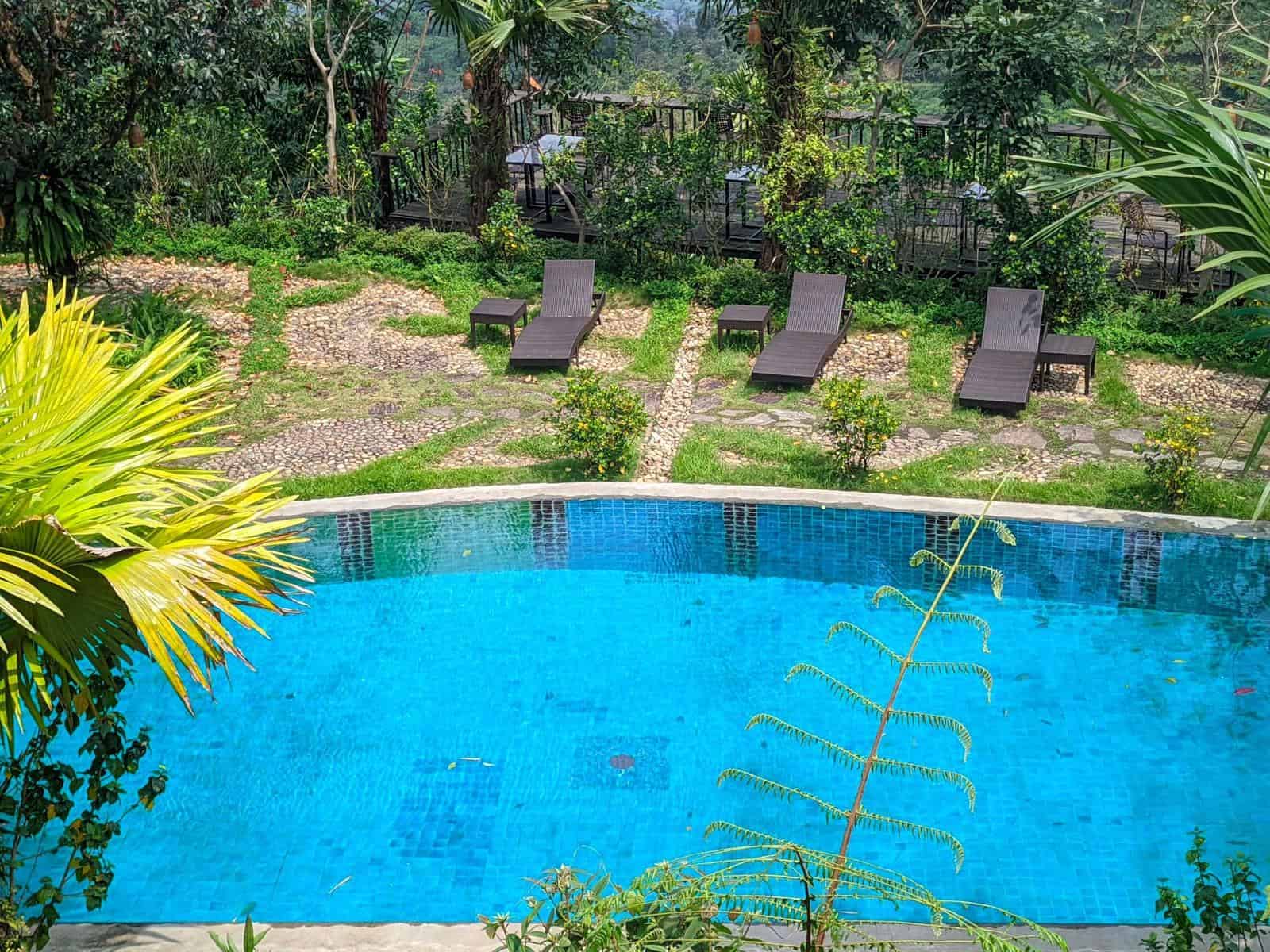 Phòng nghỉ TVPalm Ecolodge Hà Giang 14 Bể bơi nước suối xanh ngọc nhìn từ trên cao, ghế nằm bên bãi sỏi tại TVPalm Ecolodge