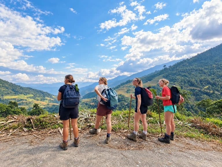Four trekkers looking over the valley under a blue sky