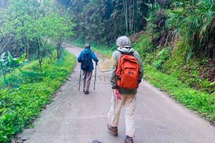 Hikers on a trail leaving Dao Ao Dai Villages surrounded by lush greenery